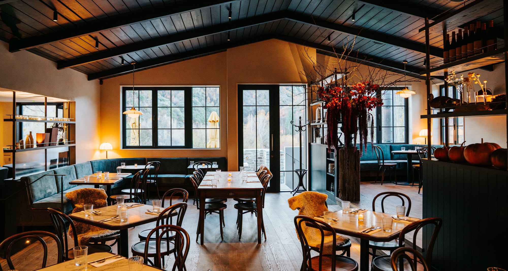 Swiftsure dining room by Titan Furniture — a continuous curved velvet banquette wrapping the bay windows above the Arrowtown valley.